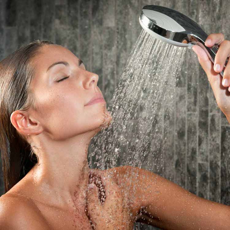 Frau duscht mit Handbrause